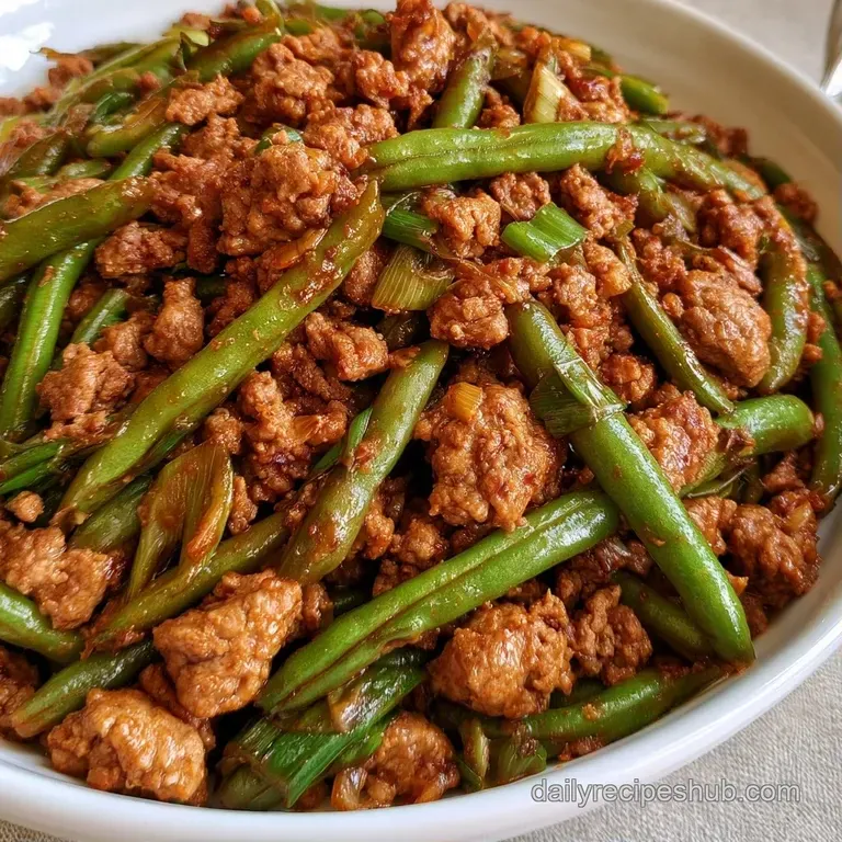 A modern white bowl filled with savory browned crumbles and crisp vegetables, garnished with fresh sliced scallions.